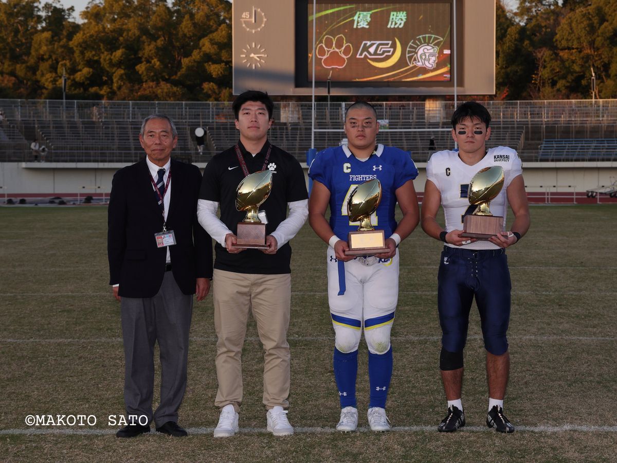 【2023年関西学生リーグDiv.1】優勝を分け合い写真におさまる川口理事と立命・関学・関大の3校主将 写真:佐藤誠