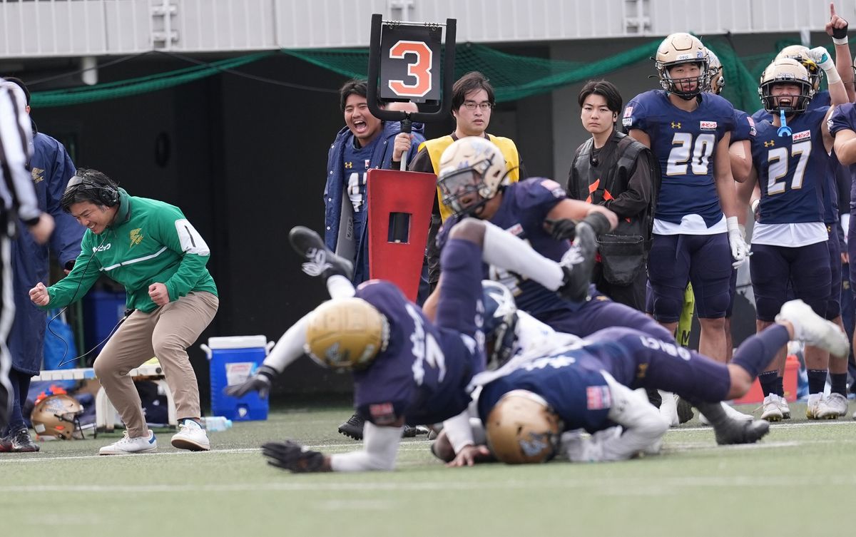 【オービックvs エレコム神戸】サードダウンでエレコム神戸QBピンデルのラッシュをロスさせてサイドラインでガッツポーズの塚田ＨＣ（左、緑のジャケット）＝撮影：小座野容斉