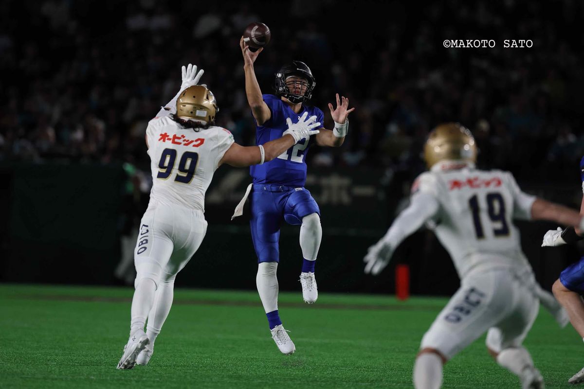 日本選手権・ライスボウル【パナソニックvsオービック】オービックDEトゥローターショーンの激しいラッシュを受けながらパスを決めるパナソニックQB荒木＝撮影:佐藤誠