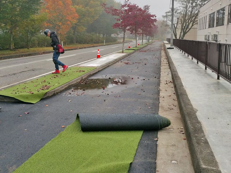 広いスペースでカットした人工芝をそれぞれ貼り付ける植栽桝の横に運び、広げる